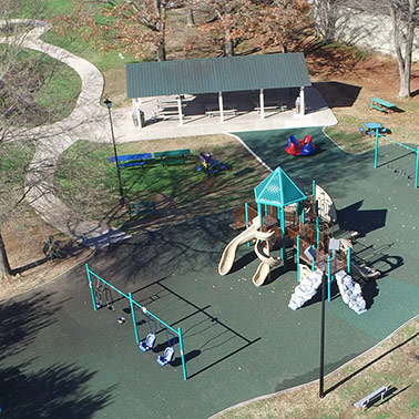 An aerial view of the swings, playground, benches, and covered pavilion at Veterans Memorial Park in Priceville, AL.