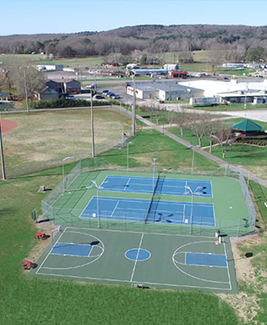 A drone view of the basketball court, two tennis courts, and outfield of the softball field located at Veterans Memorial Park.